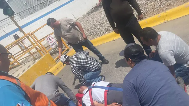 Grupo de brigadistas arrodillados atiende a un compañero tendido en el patio durante una práctica, con un arnés de rescate