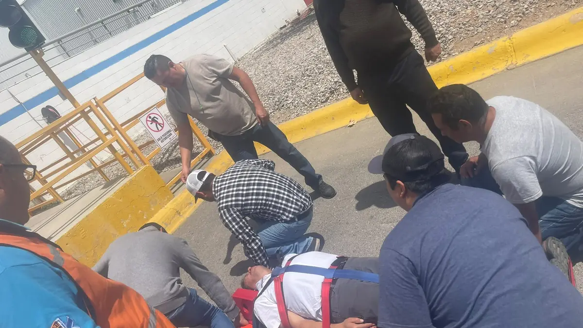Grupo de brigadistas arrodillados atiende a un compañero tendido en el patio durante una práctica, con un arnés de rescate