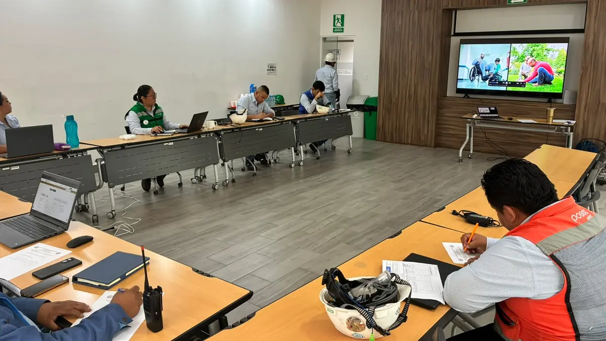Grupo de trabajadores con casco en una sesión de capacitación dentro de la planta