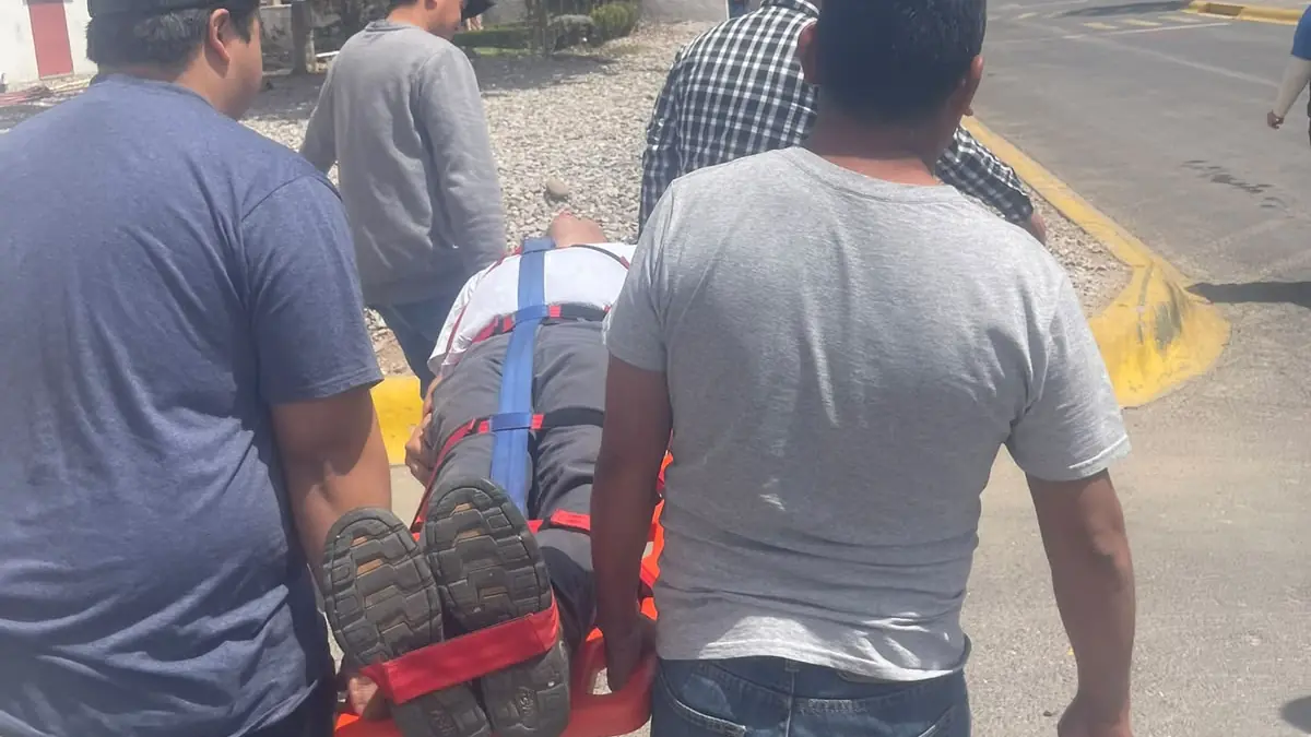 Brigadistas con chaleco y casco trasladan en camilla a un compañero durante un simulacro de emergencia en la planta