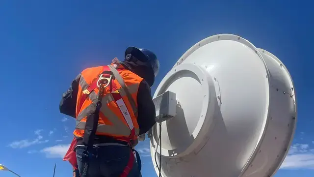 Technician in a harness and lifeline working on a structure on a rooftop