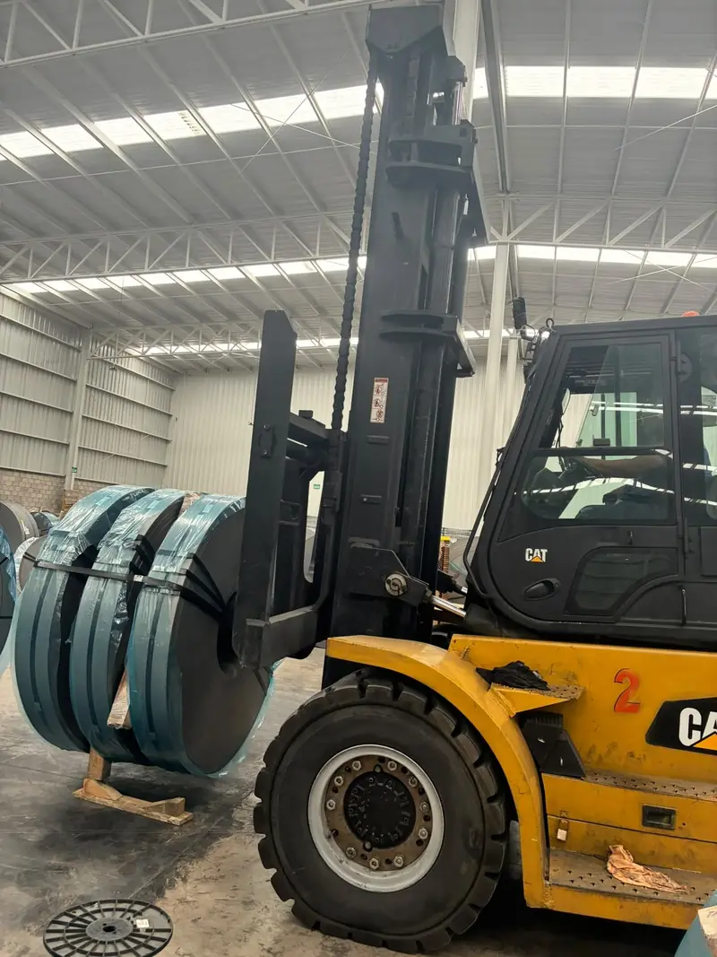 Montacargas Cat de 7 toneladas con bobinas de acero en una nave industrial