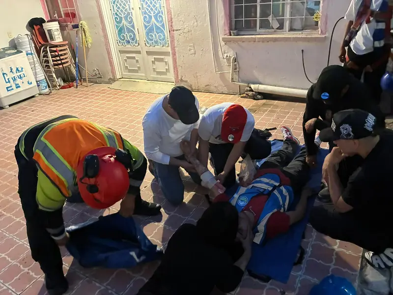 Brigadistas atienden a un participante recostado durante una práctica de primeros auxilios