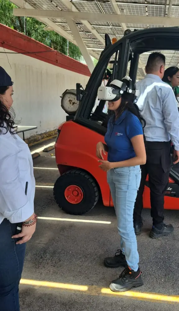 Participante con visor de realidad virtual de pie junto a un montacargas durante una demostración del simulador